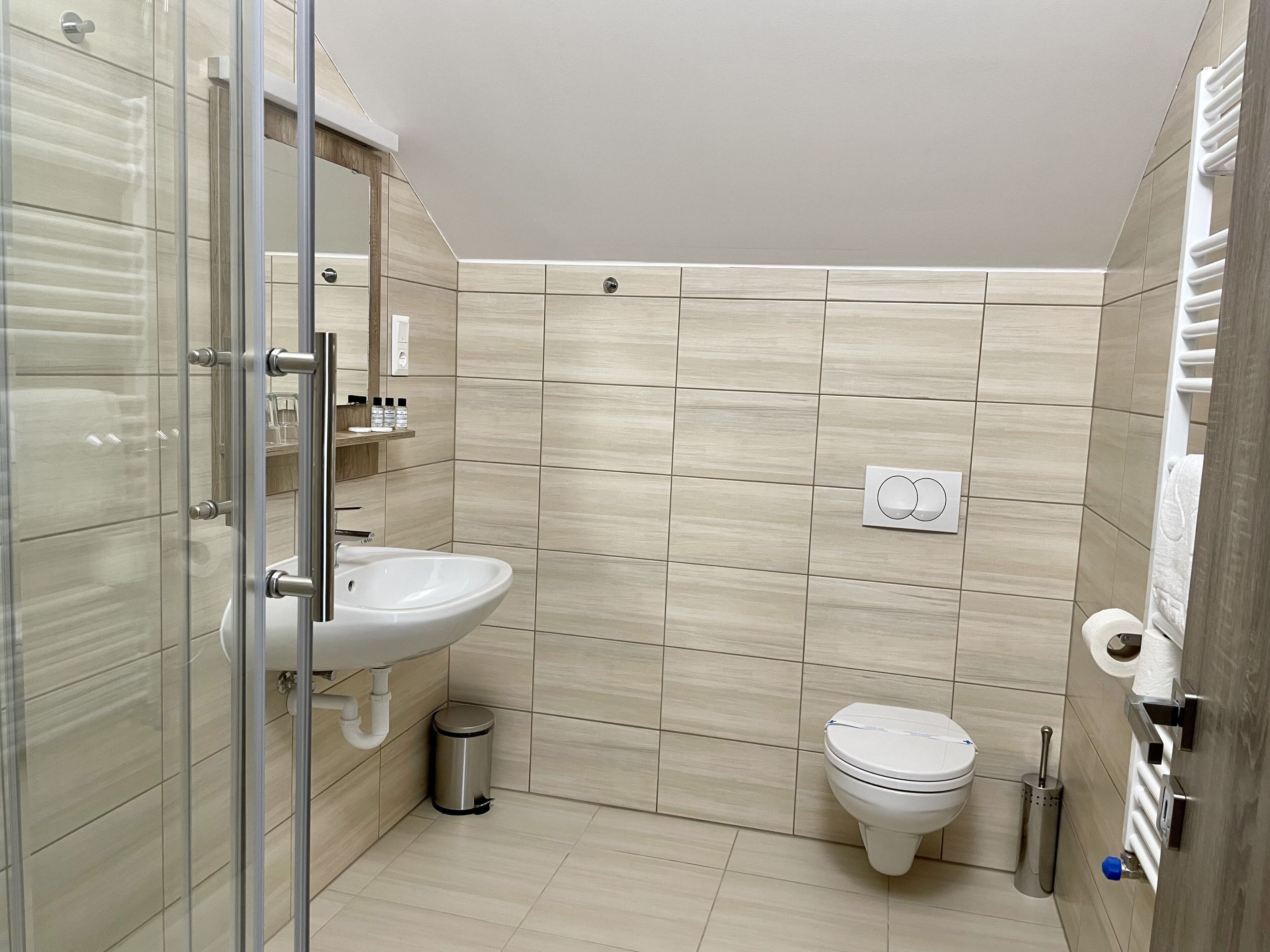 Ein modernes Badezimmer mit Duschkabine aus Glas, einem weißen Waschbecken und einer Toilette.