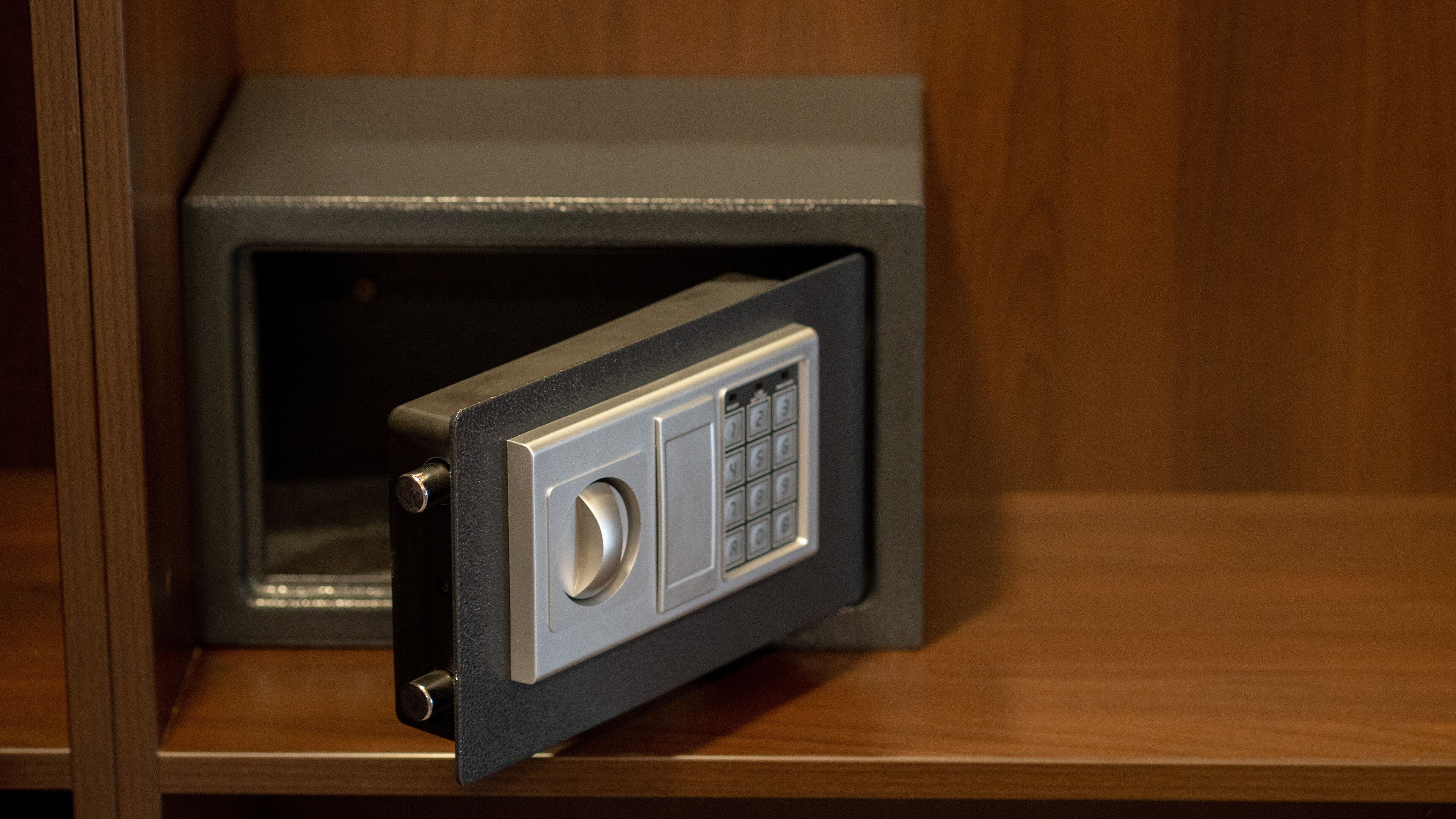 Una caja fuerte con un dial de combinación y una cerradura, ubicada dentro de un mueble de madera.