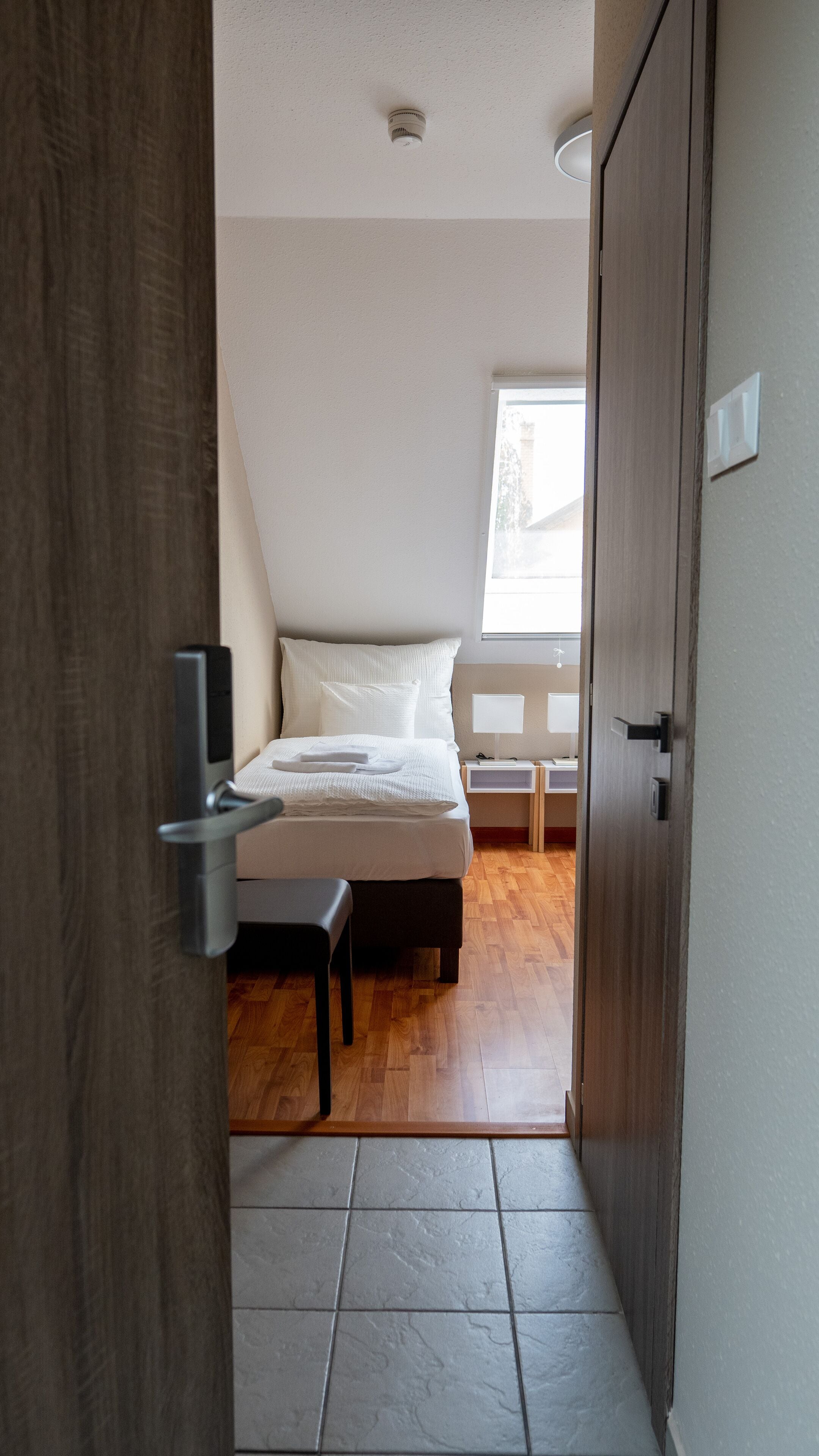 A bedroom with a bed, bedside tables, and a window.