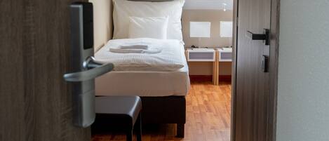 A bedroom with a bed, bedside tables, and a window.