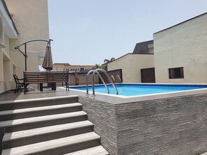 Piscina com degraus, um banco e uma cerca.