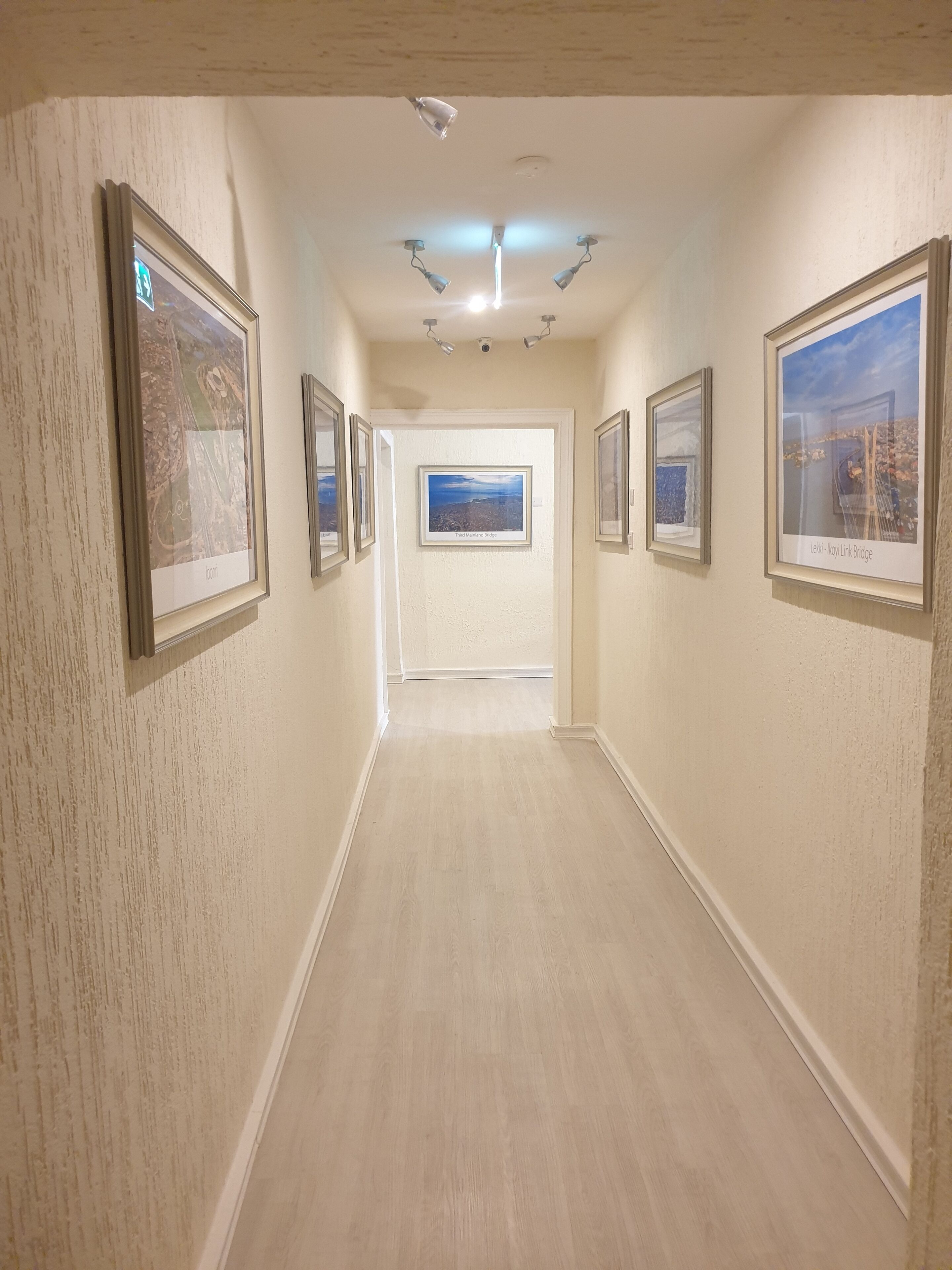A hallway with framed pictures on the walls, a ceiling fan, and recessed lighting.