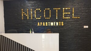 A reception desk with a black wall and a sign that reads "NICOTEL APARTMENTS". - Nicotel (Lekki)