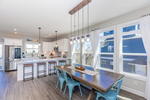 A modern kitchen with a central island, bar stools, and pendant lighting.