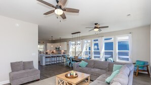 A spacious living area with a gray sofa, a wooden coffee table, and a kitchen in the background.