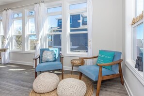 Una habitación con dos sillones azules, una pequeña mesa de madera y un otoman tejido.