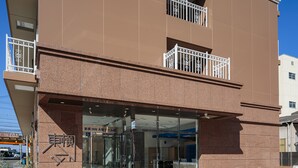 A modern building with a glass entrance, a visible sign with Japanese characters, and a metal balcony railing. - Toyoko Inn Osaka Dome Mae (Osaka)