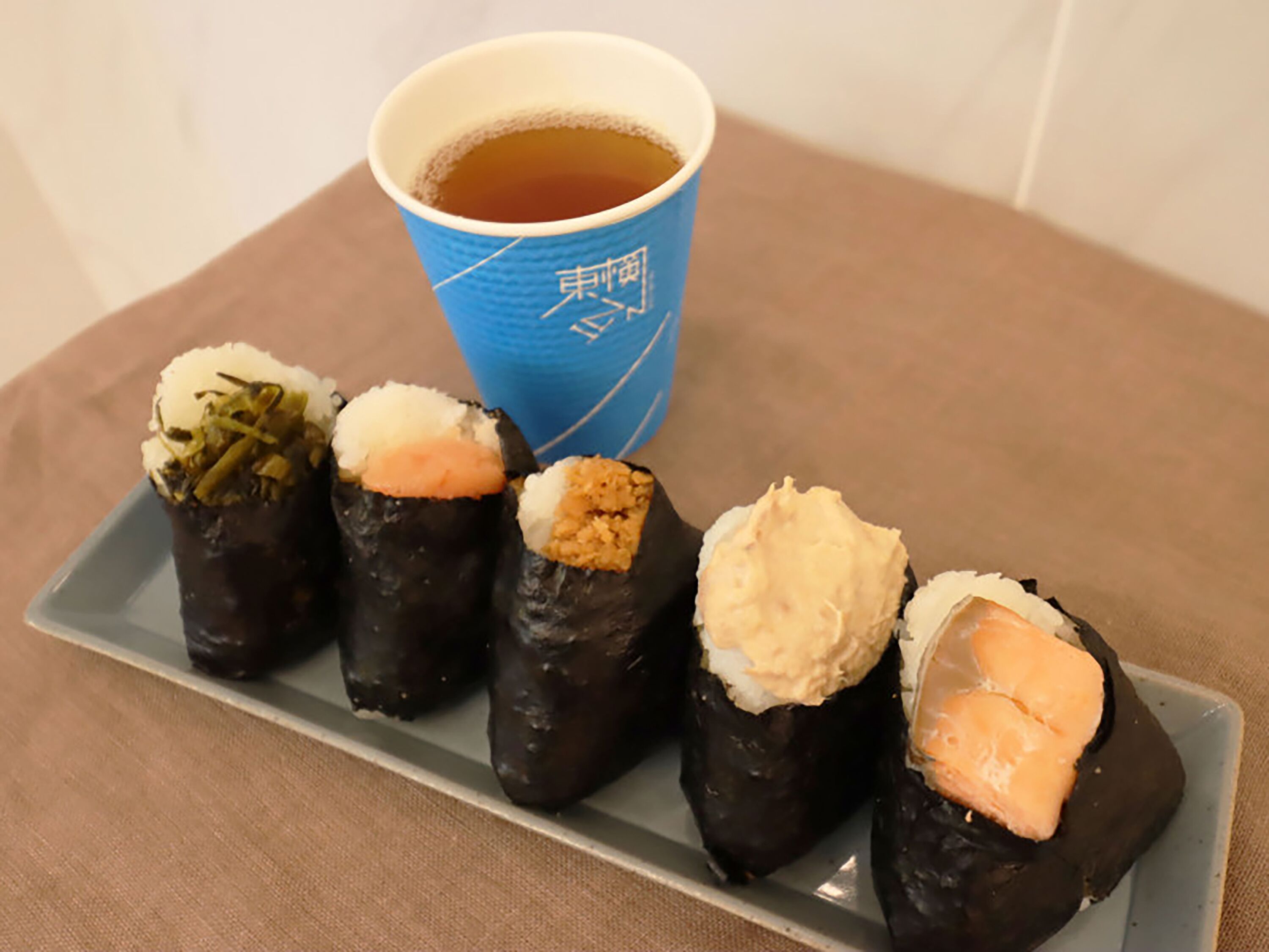 A plate of sushi with a cup of tea.