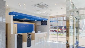 A modern hotel lobby with a reception desk, self-service machines, and a glass door leading outside. - Toyoko Inn Osaka Dome Mae (Osaka)