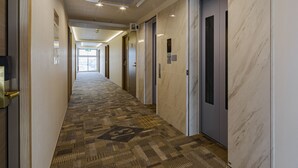 A hotel hallway with carpeted flooring, marble walls, and doors leading to rooms. - Toyoko Inn Osaka Dome Mae (Osaka)
