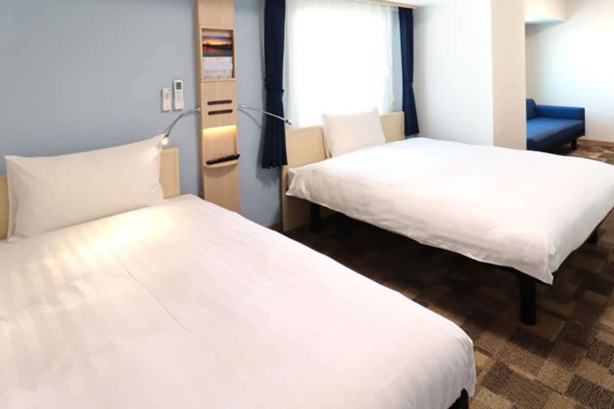 Ein Hotelzimmer mit zwei Betten, einem Schreibtisch und einem Stuhl.