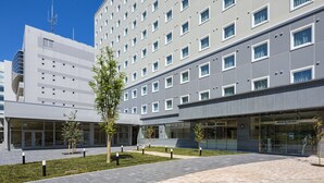 Een modern hotel met een centrale binnenplaats, meerdere verdiepingen en een gevel van glas en vaste delen.