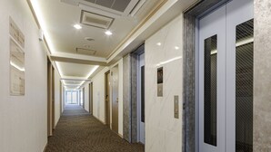 Een hotelgang met een tapijten vloer, deuren en een bordje met kamer nummers.