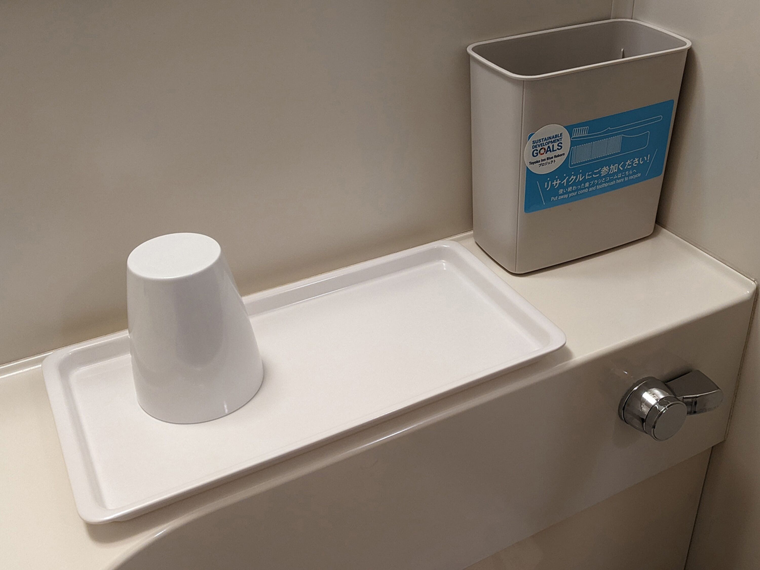 A restroom with a white urinal, a trash bin, and a soap dispenser.