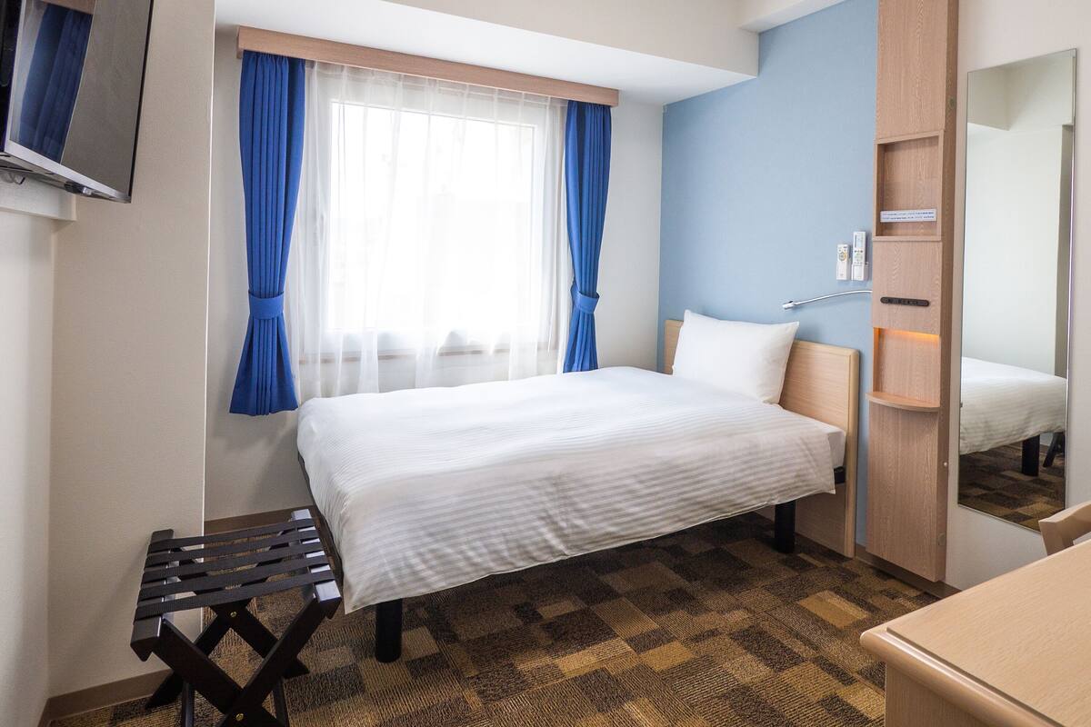 Ein Hotelzimmer mit Bett, einem kleinen Tisch, einem Spiegel und einem Kleiderschrank.