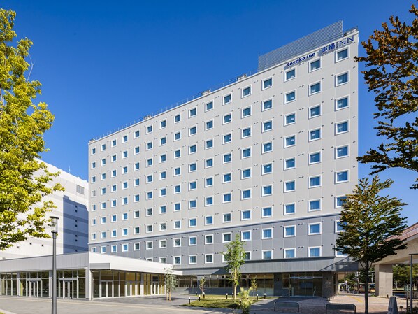 Ein modernes Hotelgebäude mit flacher Fassade, zahlreichen Fenstern und blauem Himmel.
