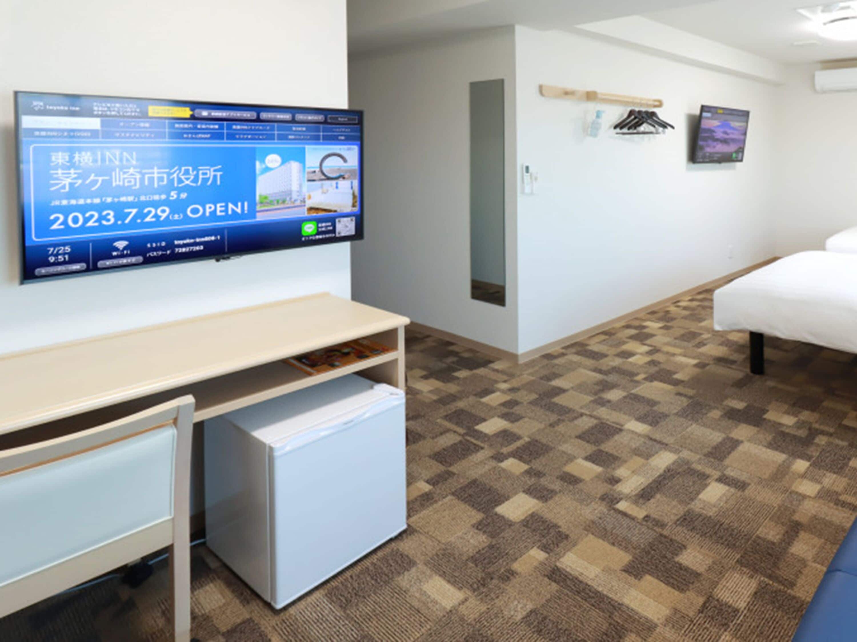 A hotel room with a bed, a desk, and a television displaying a message in a foreign language.