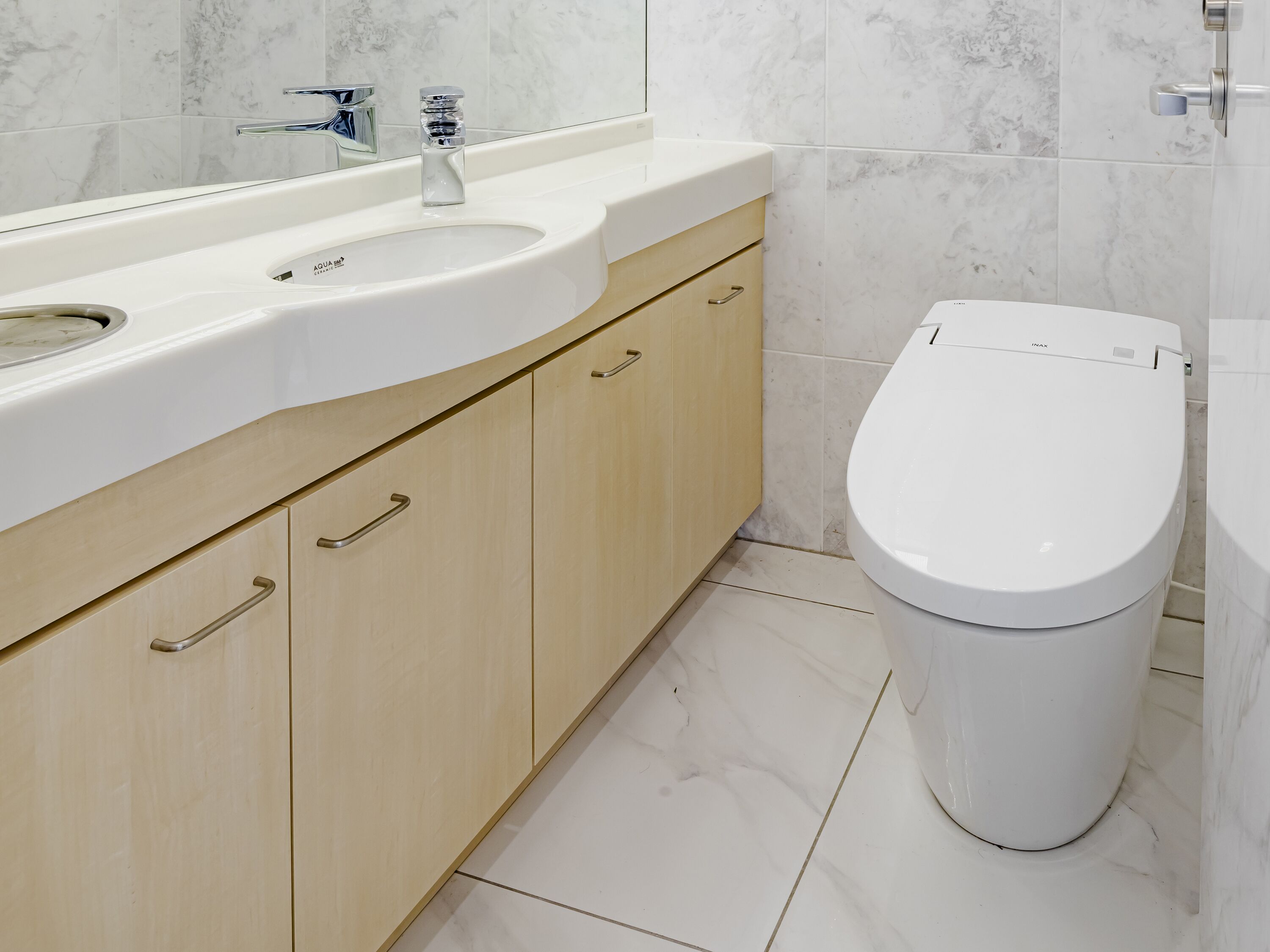 Une salle de bain moderne avec un lavabo, un meuble-lavabo et des toilettes, le tout de couleur blanche.