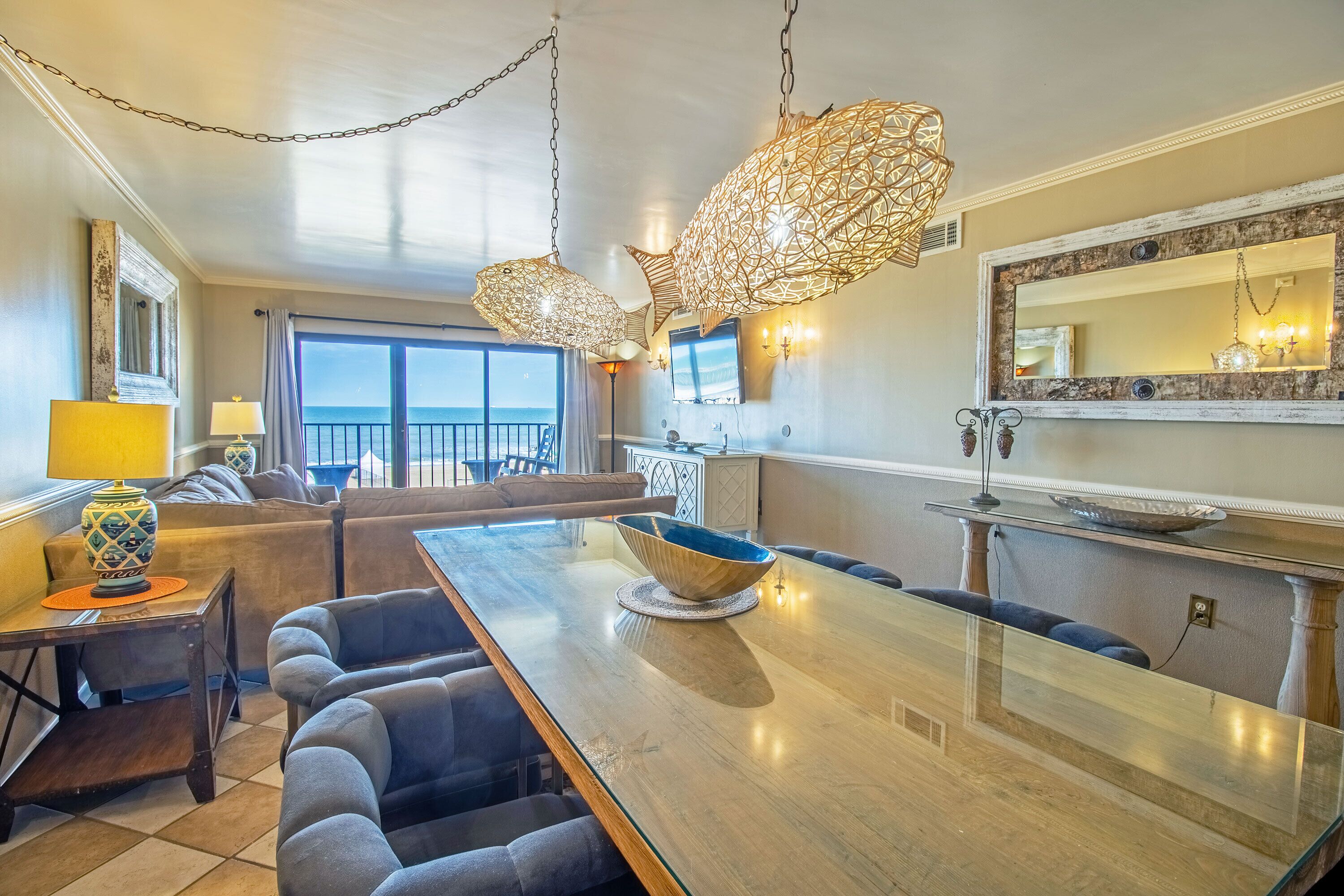A modern kitchen with a large island, pendant lights, and a view to the outside.
