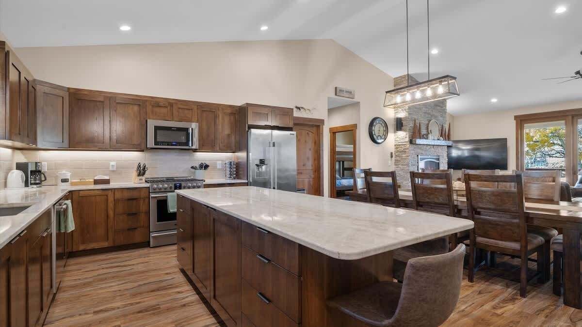 Une cuisine moderne avec des meubles en bois, des appareils en acier inoxydable et un grand îlot central.