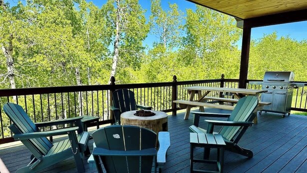 En overdækket terrasse med Adirondack-stole og grill.