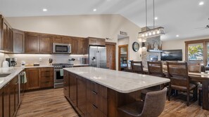 Enjoy meals in a spacious kitchen with a large island, stainless steel appliances, and a dining area.