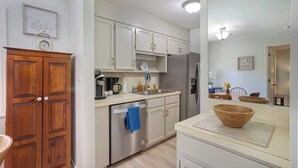 Una cocina con armarios de madera, un refrigerador de acero inoxidable y un tazón de madera sobre la encimera.