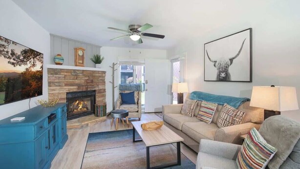 Una sala de estar con chimenea, sofá, mesa de centro y ventilador de techo.