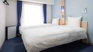 Une chambre d’hôtel avec un grand lit, une table de chevet, une commode, un radiateur fixé au mur et une fenêtre avec des rideaux bleus.
