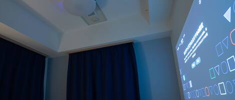Une chambre d’hôtel équipée d’un lit, d’un détecteur de fumée fixé au plafond et d’un écran de projection affichant du texte.