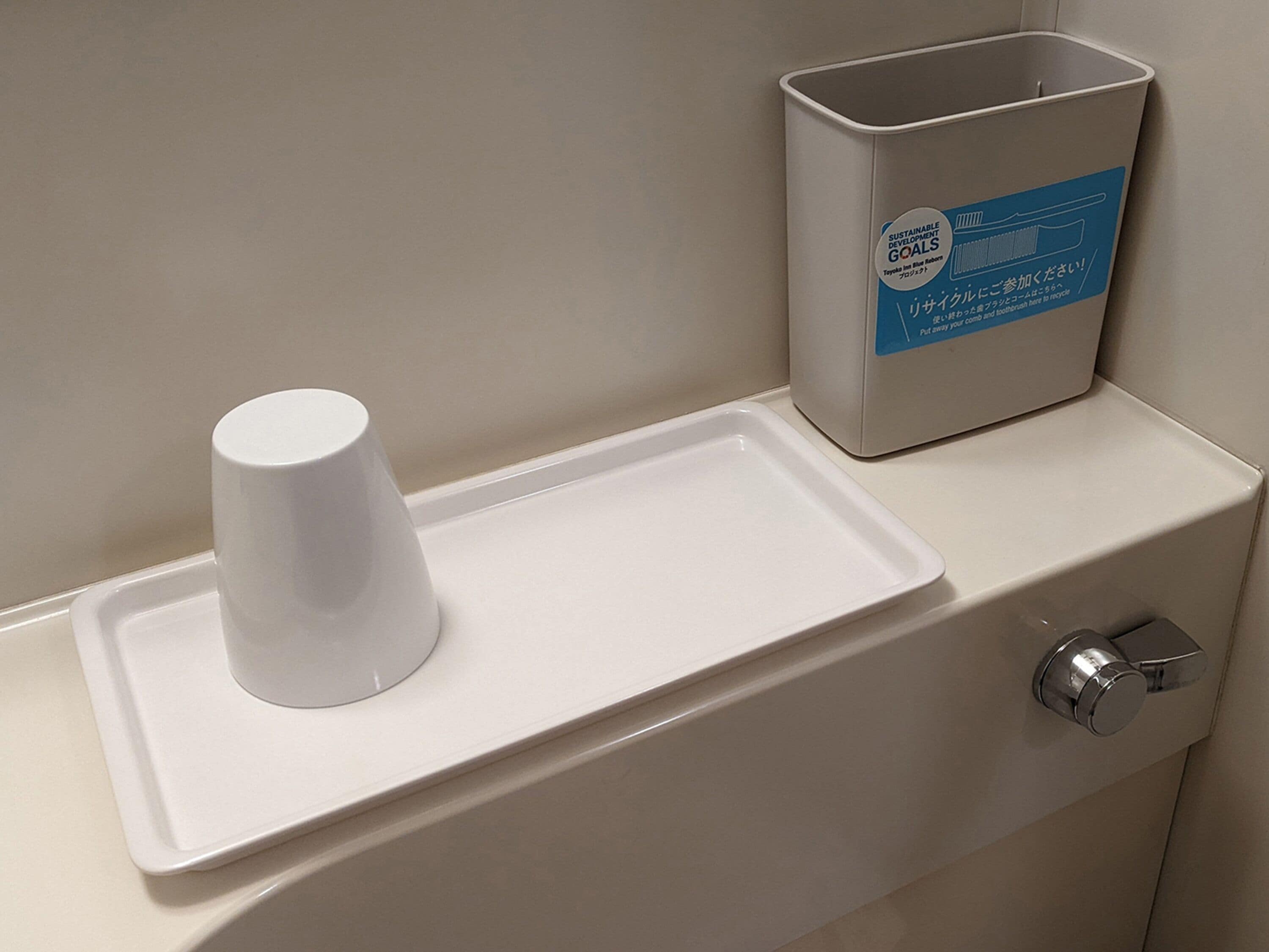 A restroom with a white urinal, a trash bin, and a soap dispenser.