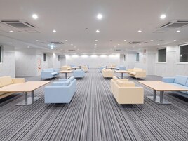 A conference room with rows of tables and chairs, a patterned carpet, and a modern ceiling design.