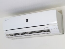 A white air conditioning unit with a control panel and a filter compartment.