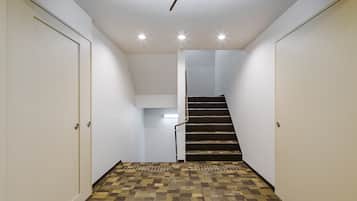 A narrow hallway with patterned carpet, white walls, and a staircase leading to an upper level.
