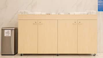 A wooden cabinet with four drawers and a trash bin with recycling symbols.