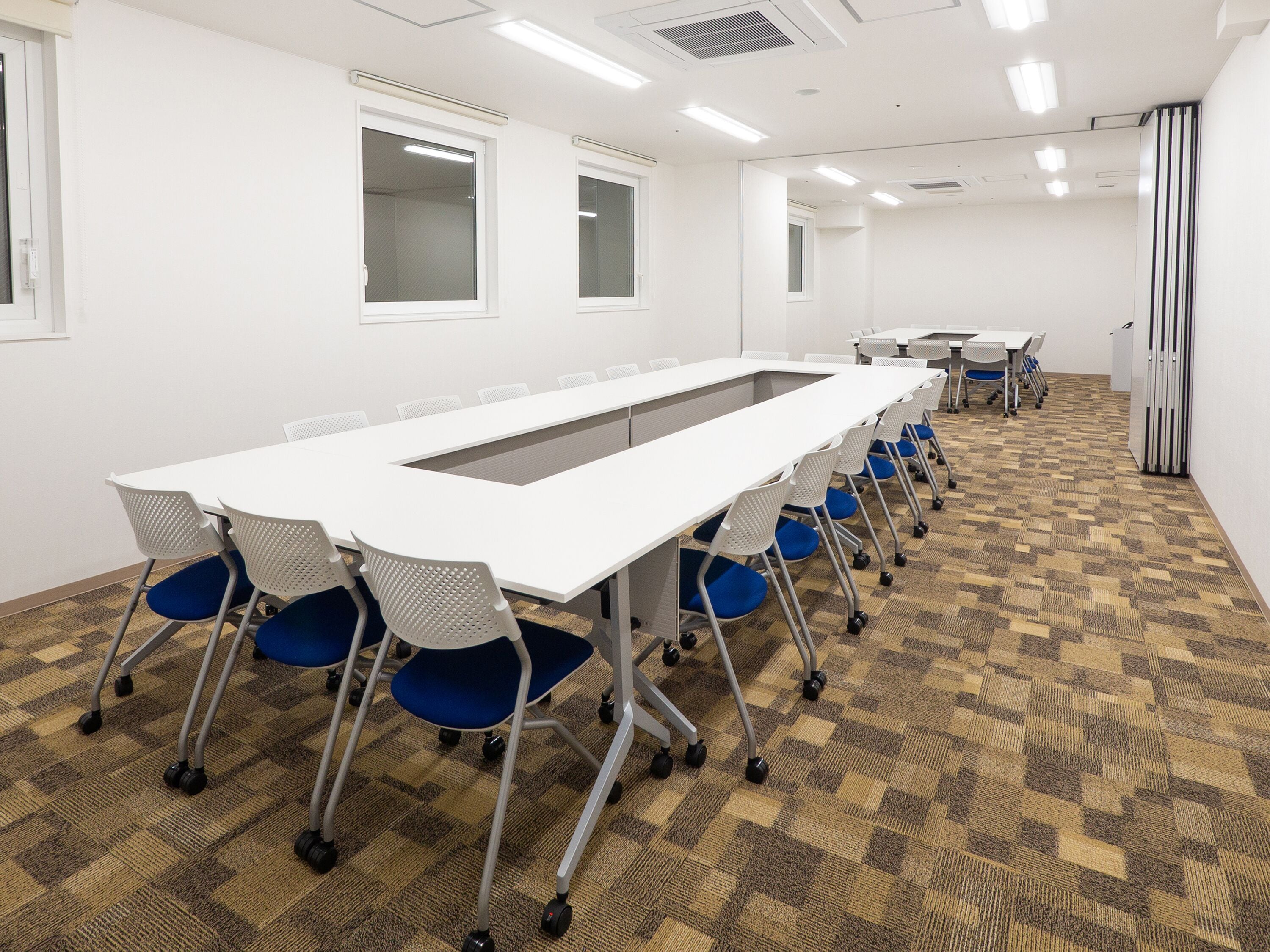 A conference room with a long table, chairs, and carpeted flooring.