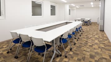 A conference room with a long table, chairs, and carpeted flooring.