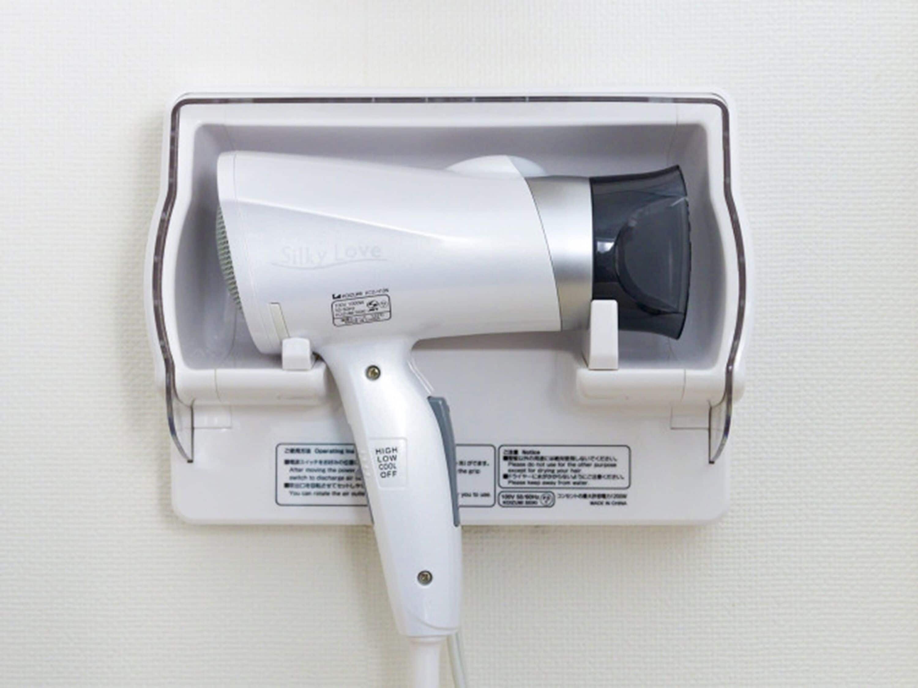 A hair dryer mounted on a wall, with instructions and warnings visible.