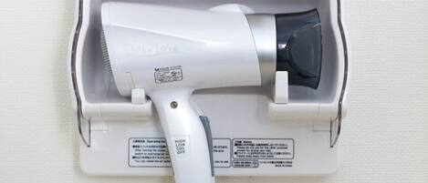 A hair dryer mounted on a wall, with instructions and warnings visible.