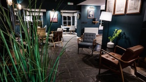A cozy lounge area with a fireplace, comfortable seating, and a view of the outdoors. - The Hope & Anchor (Ross-on-Wye)