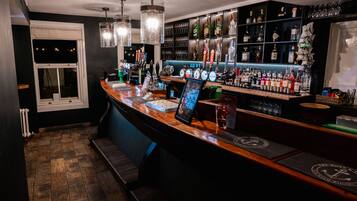 A bar area with a wooden counter, multiple liquor bottles, and a variety of glasses.
