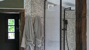 Un baño con ducha, un perchero con dos toallas y una puerta con ventana.