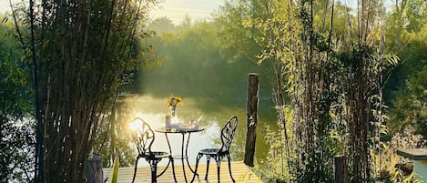 A wooden deck with two chairs and a table, overlooking a body of water.