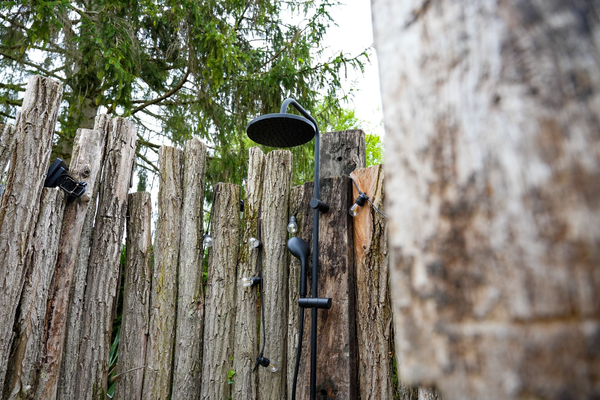A rustic wooden fence with a metal lamp post and light fixtures.