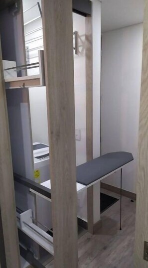 A room with a built-in bench, a white wall, and a wooden floor.