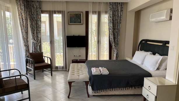 A bedroom with a bed, bedside tables, a chair, a bench, and a TV.