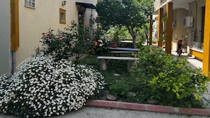 A narrow alley with a garden, a bench, and a red scooter parked on the right.