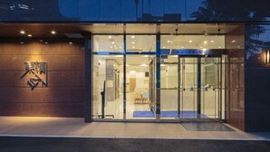 Una entrada de hotel moderna con puerta de vidrio y un letrero en idioma extranjero.