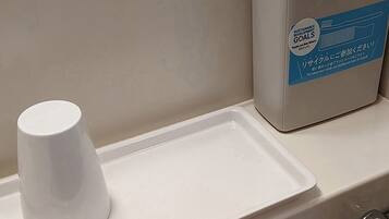 A bathroom sink with a white cup and a trash bin labeled "Sustainable Development Goals".
