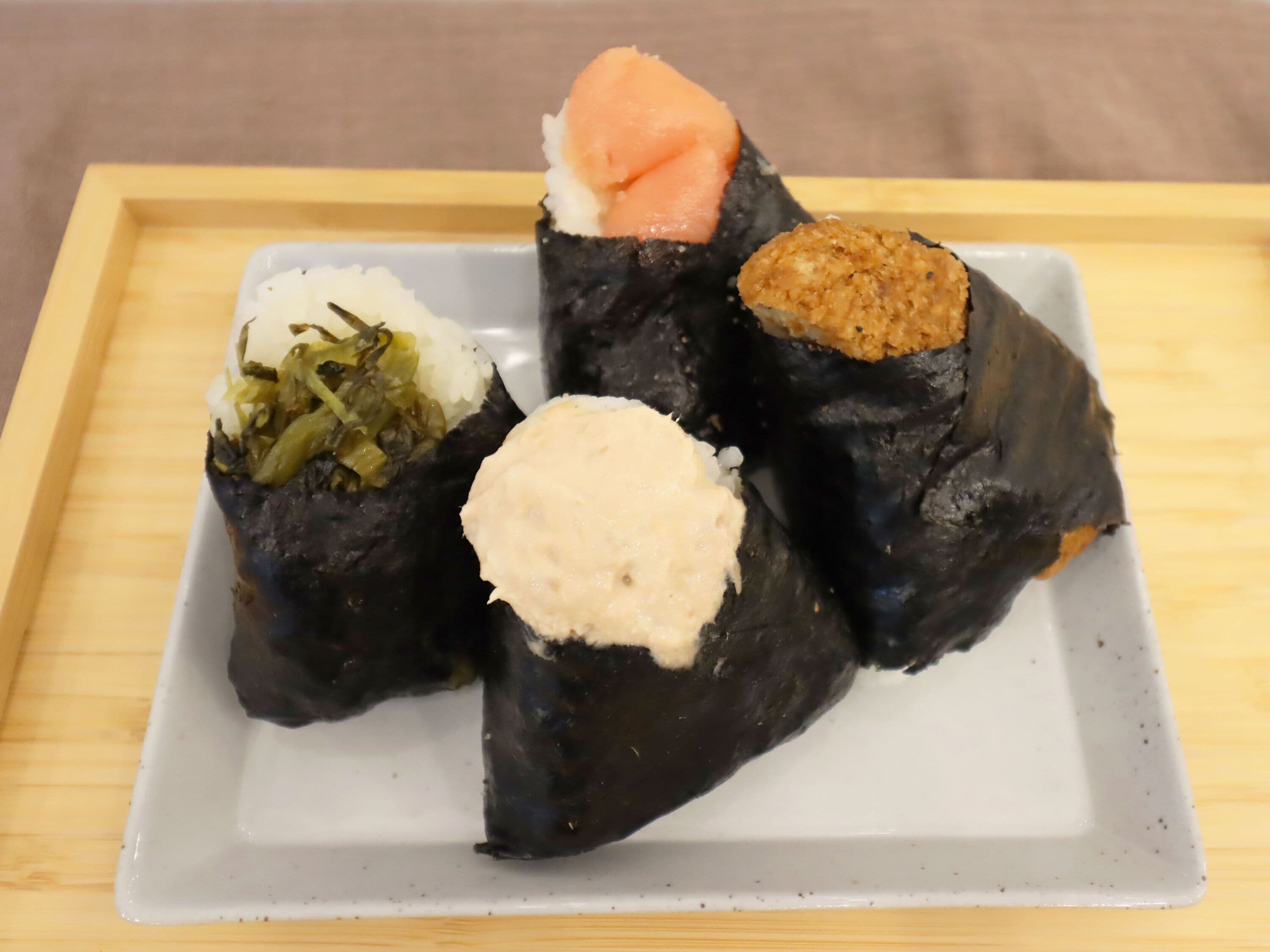 A plate with three sushi rolls, one with salmon, one with rice and vegetables, and one with a fried topping.